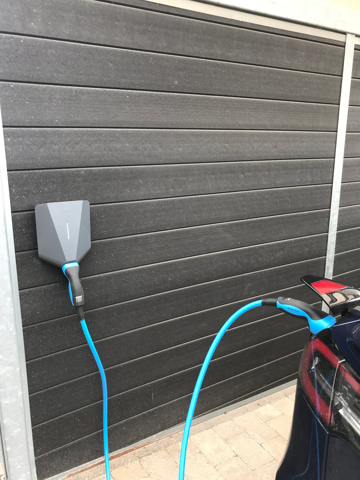 Sort Easee ladeboks monteret på sort carport med monteret blåt ladekabel til Tesla 3, front