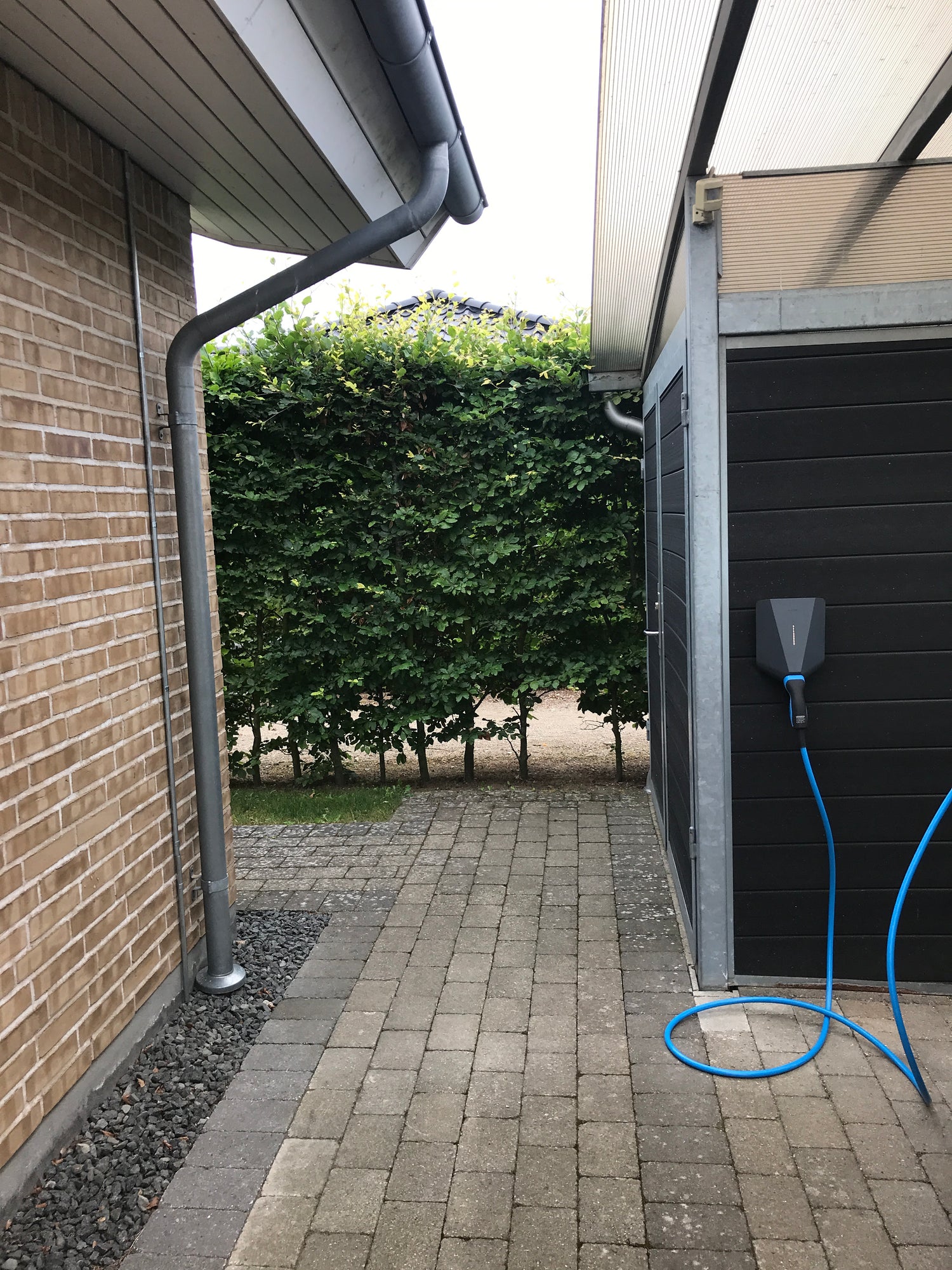 Sort Easee ladeboks monteret på sort carport med monteret blåt ladekabel, front