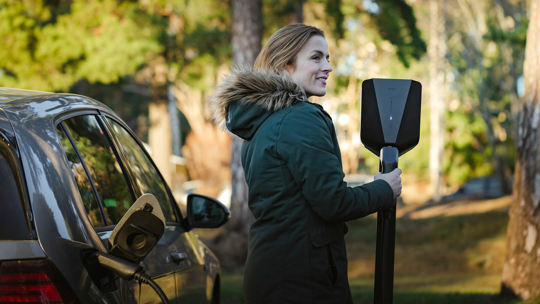 Kvinde oplader elbil med Easee ladeboks, front
